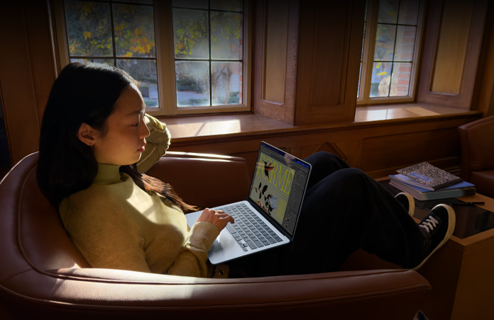 Une personne assise dans un fauteuil utilise un MacBook Air