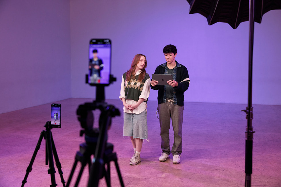 To iPhone 17 Pro Max-enheter på stativer filmer Kyle Hanagami og en danser i et studio. Hanagami holder en iPad Pro.