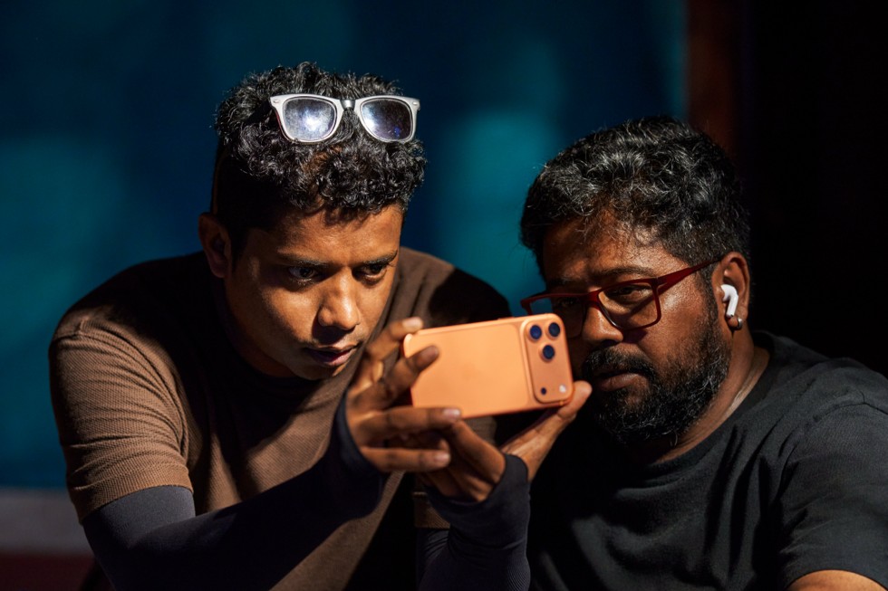 Robin Joy and a colleague look intently at iPhone 17 Pro Max.
