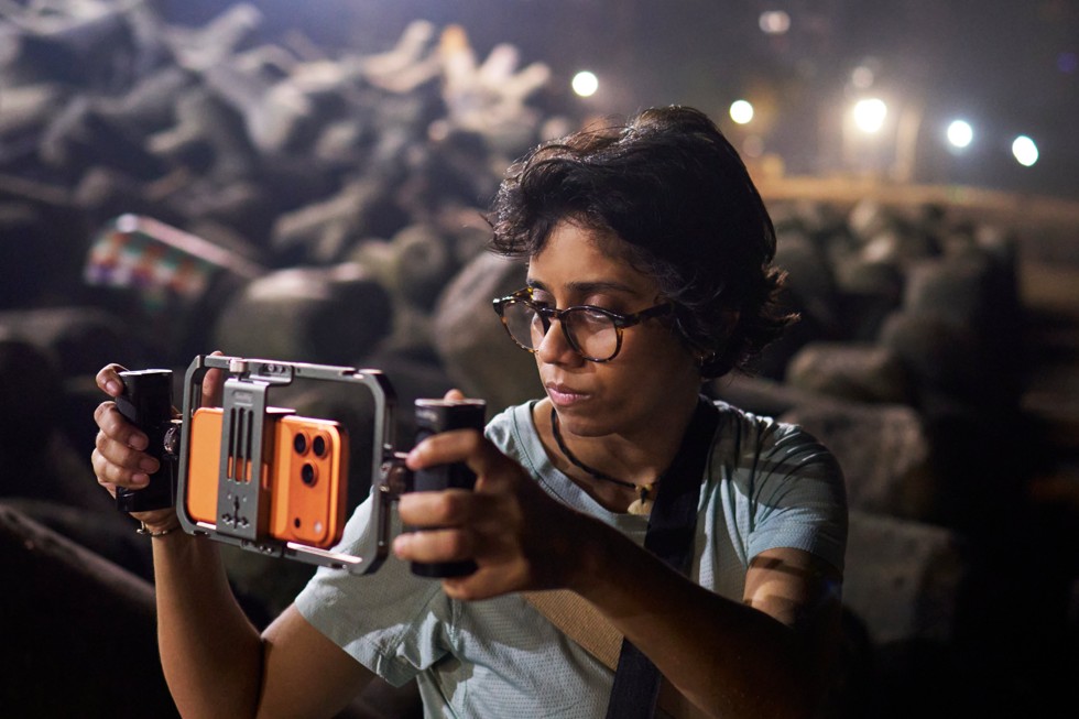 Shreela Agarwal holds a camera rig with iPhone 17 Pro Max attached, filming outdoors at night.