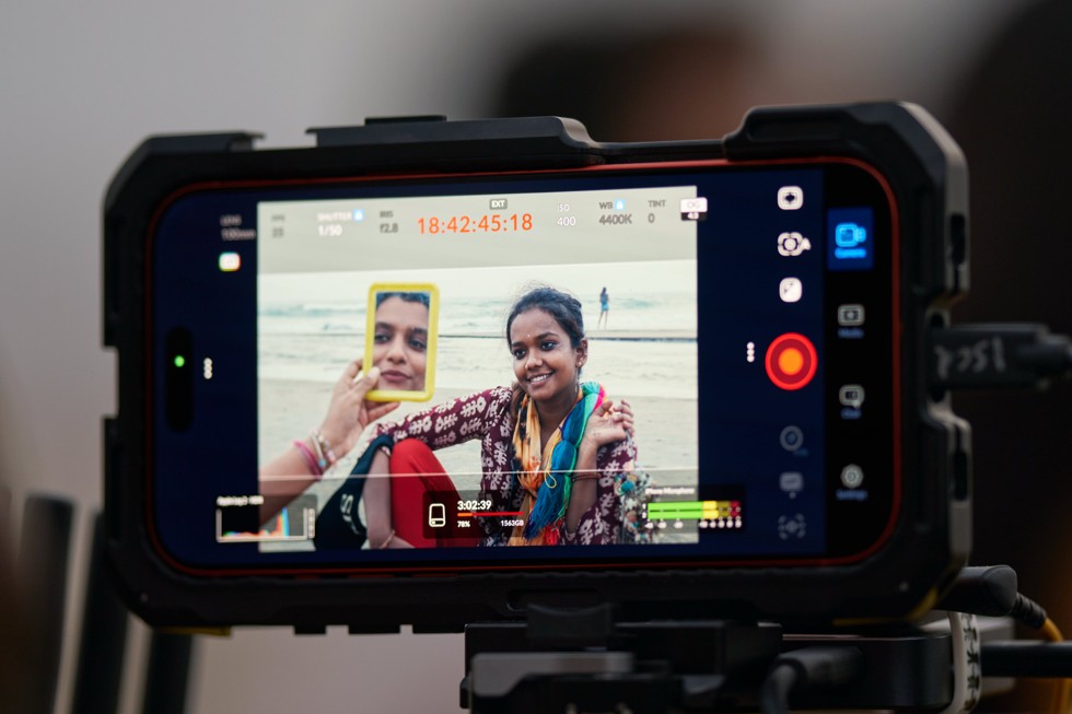 A close-up of an iPhone 17 Pro Max screen in a rugged case, showing the camera app recording a person.