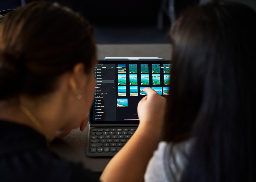 圖片顯示後方兩人使用 iPad 編輯照片。