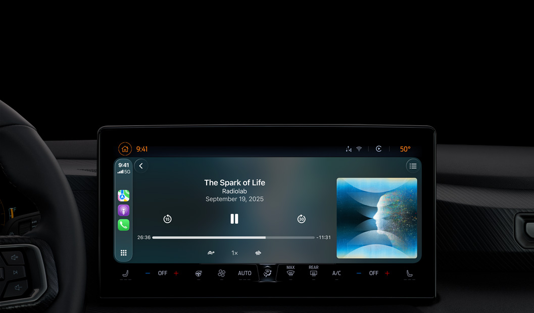 A car interior, center console display shows Apple Podcasts playing via CarPlay, now playing "The Spark of Life" podcast by Radiolab, playback controls include skip back, pause, and skip forward.