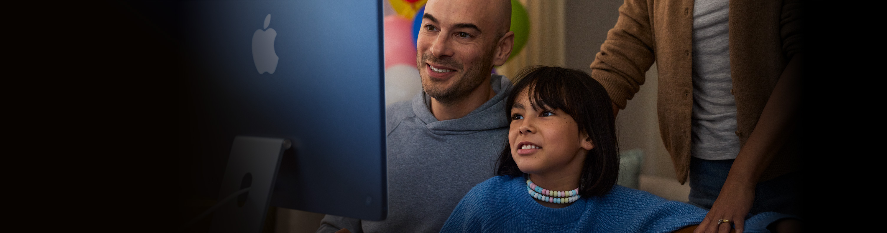 A child uses an iMac at home with adult supervision.