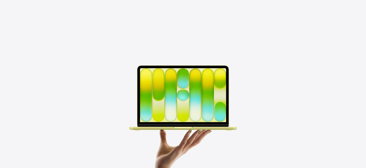 開いた手の指先が明るいシトラスのMacBook Neoをバランス良く支えている。画面にはカラフルで抽象的なパターンが表示されている